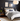 Moderne slaapkamer met grijs dekbedovertrek, houten bed, zwarte muur, wandlampen, en kunstwerken.