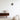 Moderne zwarte wandlamp op witte muur in minimalistisch interieur met houten dressoir en decor.