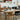 Moderne eetkamer met houten tafel, diverse stoelen, en design tafellamp in Scandinavische stijl.