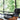 Zwarte leren fauteuil met houten details naast witte Nelson tafellamp op glazen bijzettafel.