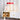 Rode tafellamp op witte kast, messing details, moderne interieurdecoratie, designverlichting.