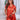 Vrouw in oranje satijnen pyjama set met korte mouwen en hartdetail, lachend in keuken.