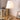 Tafellamp met witte kap en messing voet op houten bureau naast boeken en schilderij.
