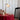Antieke tafellamp met gouden voet en witte kap op tafel met rood tafelkleed en decoratieve items.
