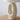 Beige keramische tafellamp met ovale voet op houten tafel, moderne interieurverlichting.