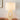 Beige tafellamp met ovale keramische voet en witte stoffen kap op houten tafel.