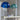 Twee moderne tafellampen met blauwe en groene kap op witte tafel, glazen accessoires.
