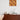 Witte tafellamp op houten dressoir met retro kunstwerk en keramisch theeservies.